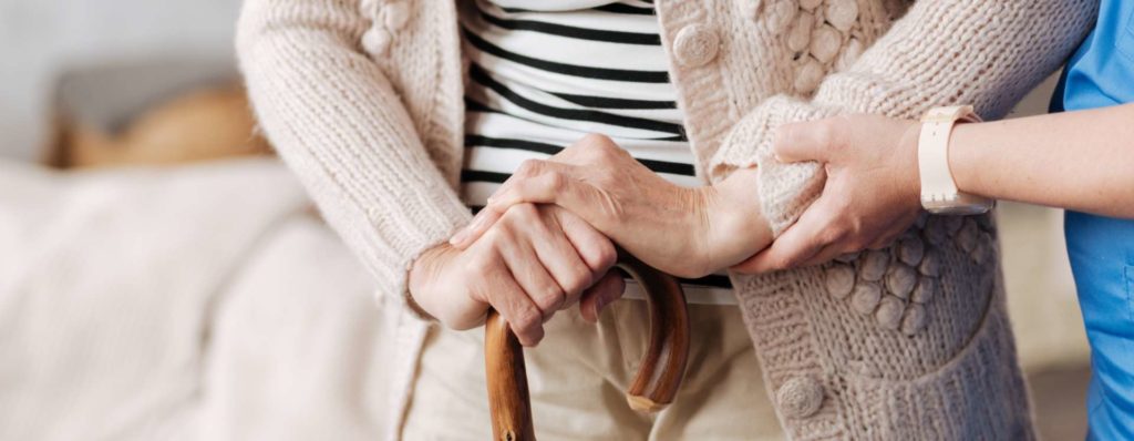 carer helping elderly woman to stand